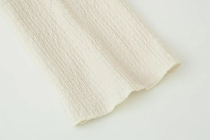 Close-up of cream white textured seersucker fabric with waffle-like bubbly pattern