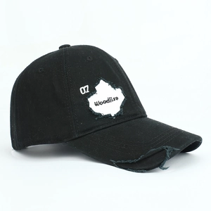 Close-up of distressed ripped details and embroidery on a black washed cotton baseball cap
