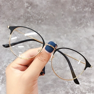 Dettaglio di occhiali vintage rotondi in nero e oro con eleganti aste in metallo