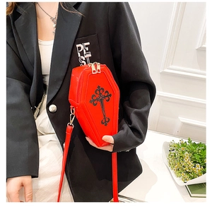 Detail of red coffin-shaped crossbody bag with black cross print and metal zippers