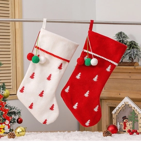 Detail of red and white velvet Christmas stockings with embroidered tree and pom-poms