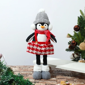 Close-up of a Christmas penguin doll with knitted hat and red plaid skirt by a festive tree