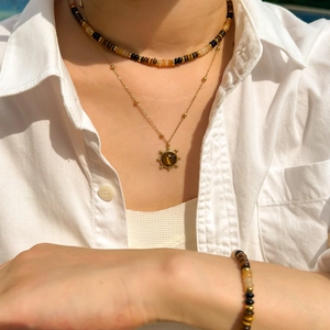 Tiger eye beaded necklace and bracelet set with golden sun pendant on a female model