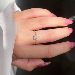 Gros plan d'une bague chaîne plaquée or 18k avec émeraude en forme de poire sur doigt