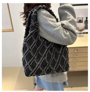 Detail view of black denim tote with frayed diamond quilting and casual shoulder strap