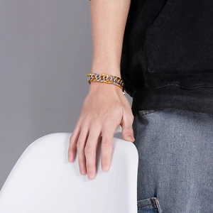 Close-up of a chunky gold and silver Cuban chain bracelet worn on a man's wrist