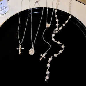 Y2K silver cross and pearl necklace set with religious pendants on a black tray