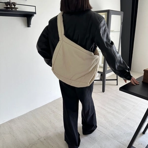 Model wearing a large beige puffy sponge tote bag with soft padded shoulder straps