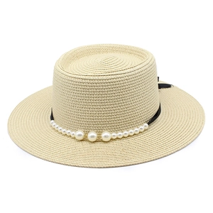 Dettaglio di cappello in paglia con eleganti decorazioni di perle e nastro nero