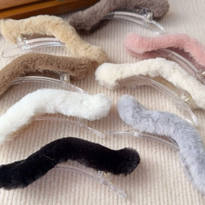 Detailed view of plush wavy hair clips in multiple colors on beige knit fabric background