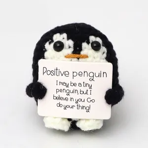 Handmade crochet penguin plush doll with motivational message card on white background