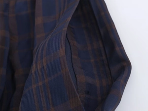 Detailed close-up of blue and coffee plaid twill fabric on the casual puff trousers