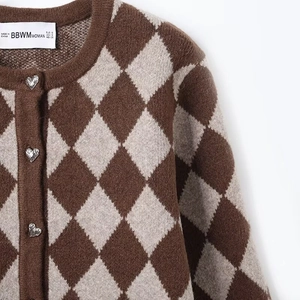 Detail of argyle knit cardigan featuring exquisite silver heart-shaped metal buttons