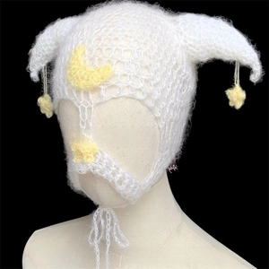 Detail of white handmade crochet devil horn hat featuring yellow moon and star patches