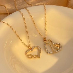 Infinity heart necklaces with gold plating and sparkling crystals on ceramic plate