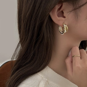 Elegant geometric C-shaped double hoop earrings with gold and white resin rings worn by a model