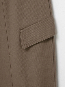 Gros plan détaillé du coton sergé marron foncé et des coutures précises sur la poche du pantalon