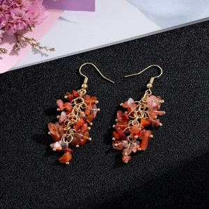 Macro shot of handmade natural stone long tassel earrings with red orange crystals