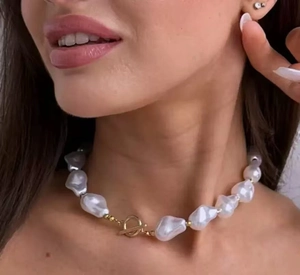 Detailed close-up of Baroque pearl necklace with gold T-bar toggle clasp on collarbone