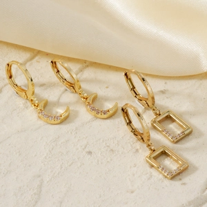 Detailed close-up of gold moon and rectangle earrings with sparkling cubic zirconia stones