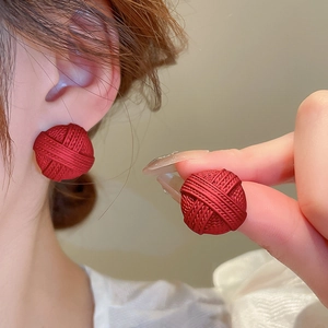 Close-up of red woven texture button earrings with a matte geometric round design