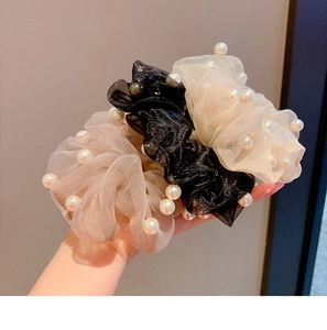 Detailed view of organza hair scrunchies with white pearls in champagne, black, and beige