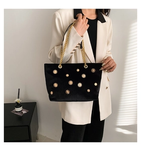 Détail du sac cabas en velours noir avec rivets soleil dorés et bandoulière chaîne