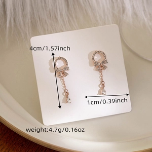 Detail of rose gold bow earrings with crystal teardrops showing 4cm length and 1cm width