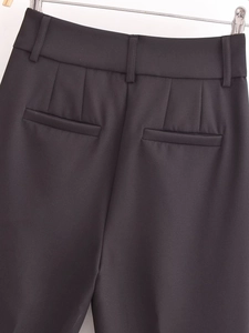 Detail of high-waist dress pants featuring rear darts and welt pockets in black