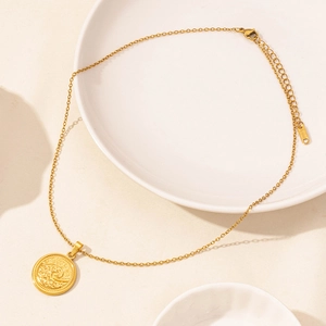 Detailed close-up of a gold stainless steel round pendant with wave relief and adjustable chain