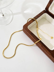 Detail view of a gold snowflake chain necklace elegantly draped over a wooden jewelry box