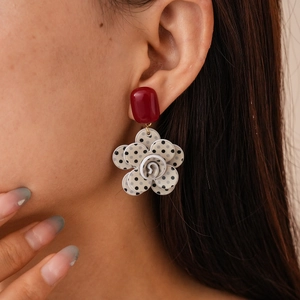 Close-up of retro acrylic earrings with red square studs and black polka dot flower petals