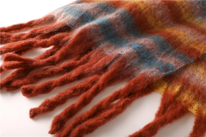 Close-up of thick tassels and soft striped knit texture on a colorful winter scarf