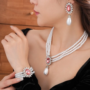 Détail de parure collier et boucles d'oreilles en perles avec fleurs roses et perles