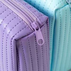 Detail shot of the zipper and vertical quilted stitching on the purple makeup bag
