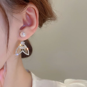 Gros plan de boucles d'oreilles queue de poisson avec perles et zircons sur un modèle