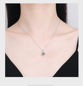 Close-up of 2 carat round moissanite halo pendant on silver chain worn by a model