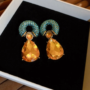 Detailed macro view of vintage baroque gold earrings with amber crystal drop and turquoise stones