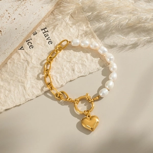 Goldenes Gliederkettenarmband mit weißen Perlen und Herzanhänger auf Steinbasis