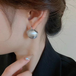 Close-up of S925 sterling silver ball earrings with a matte brushed metal texture on model