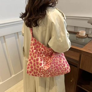 Sac cabas en toile à imprimé léopard rose porté par un mannequin dans un café