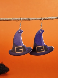 Close-up of purple witch hat earrings with gold buckles hanging on a twig for Halloween