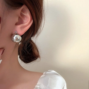 French style minimalist silver spherical metal earrings worn by a model in close-up