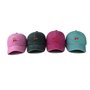 Detail of embroidered cherry patterns on four washed cotton baseball caps in various colors
