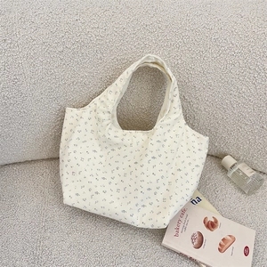 Close-up of floral corduroy tote bag featuring blue and lilac patterns on beige fabric