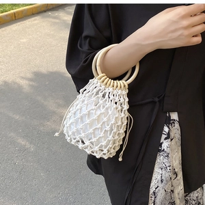 White cotton rope woven beach bag with round wooden handles and inner drawstring pouch