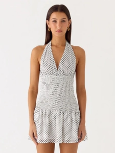 Detailed view of the smocked waist and halter neck on the black polka dot mini dress