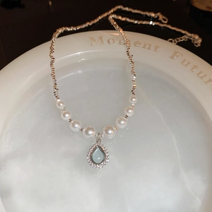 Detail of water drop zircon pendant and white pearls on a stylish silver chain