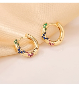 Detailed macro shot of gold huggie earrings with colorful inlaid zircon stones