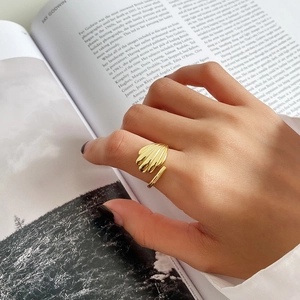 Detail of a gold adjustable shell-textured ring worn by a model over a photography book